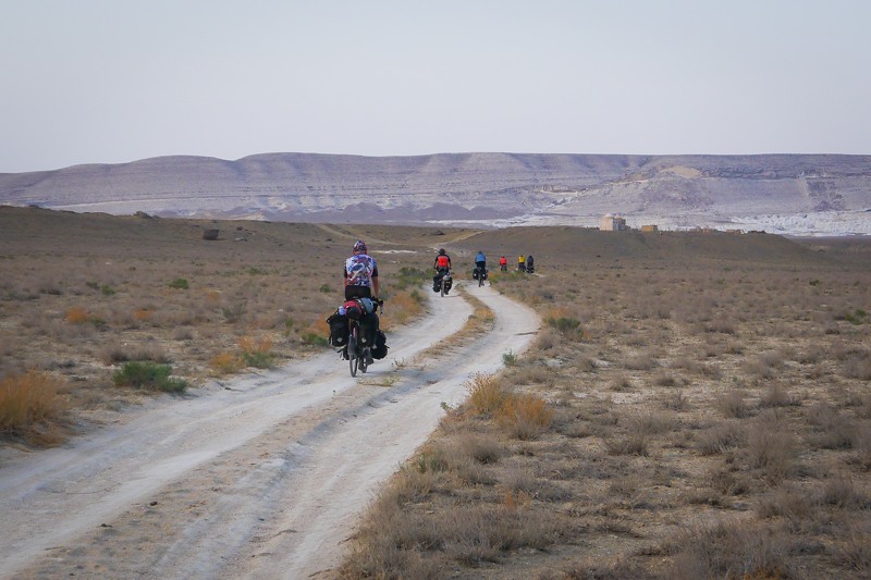 cycling across a track road in the Kazakhstani desert